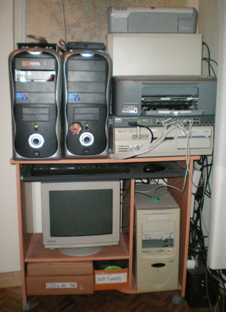 Laboratorio de GuilleSQL: Esta imagen muestra el Laboratorio de Guille SQL. Los servidores de color negro son los HOST de Máquinas Virtuales, y alrededor, tenemos otros tres equipos de color blanco, el switch, las impresoras, el SAI (abajo a la derecha), el router ADSL, el DVD externo USB, etc.